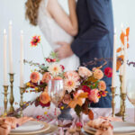 Autumn wedding concept. Bride and groom near decorated table with autumn flowers, candles and table setting